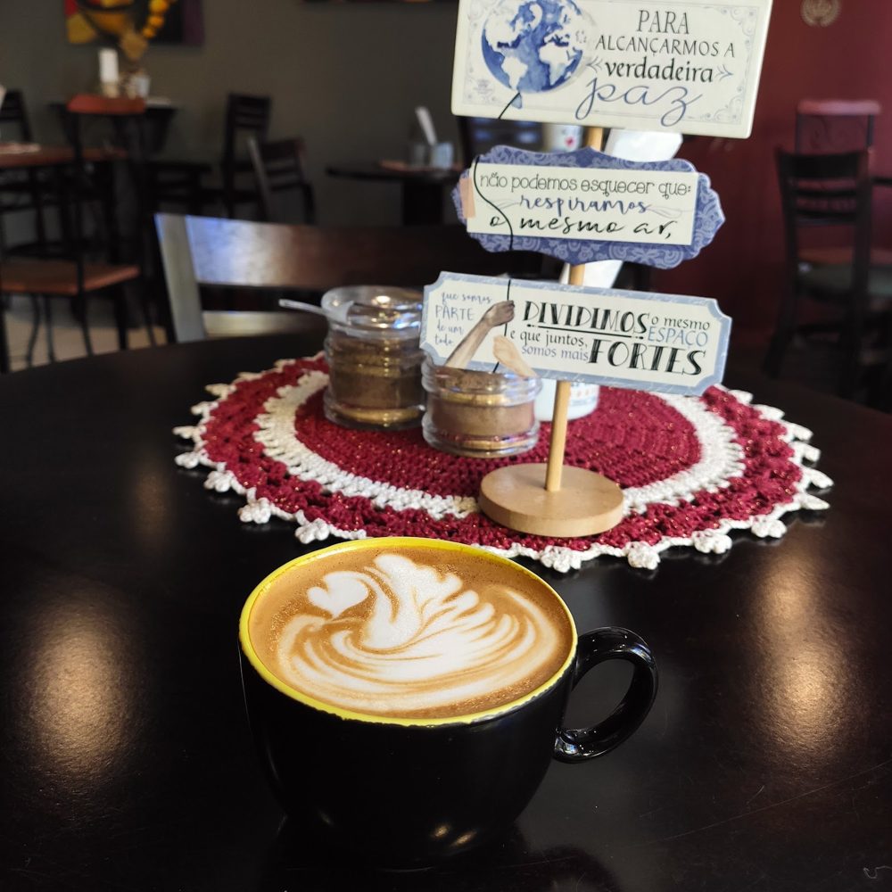 Café com arte de cisne numa mesa com toalhinha de crochê